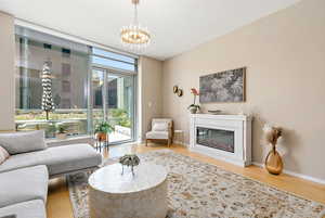 Living room featuring wood finished floors, expansive windows, a glass covered fireplace, and a chandelier