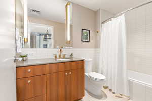 Full bath featuring vanity, tile patterned floors, tile walls, and shower / tub combo with curtain