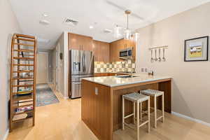 Kitchen featuring a peninsula, stainless steel appliances, brown cabinets, light wood-type flooring, and recessed lighting