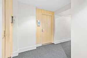 Hall featuring dark colored carpet