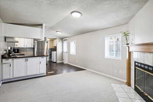 Kitchen with washing machine and clothes dryer, dark countertops, a fireplace, vaulted ceiling, and a textured ceiling