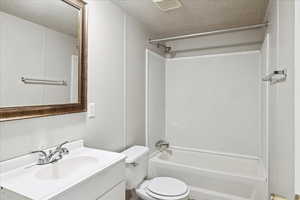 Full bath featuring a textured ceiling, vanity, and tub / shower combination