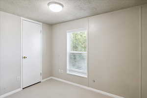 Spare room featuring a textured ceiling and light colored carpet
