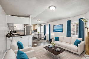 Living area featuring light wood-style floors, healthy amount of natural light, and vaulted ceiling