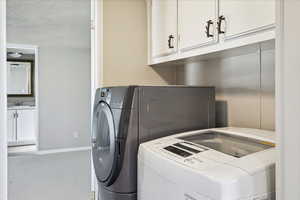 Laundry area featuring cabinet space, washing machine and clothes dryer, and a textured ceiling