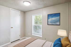 Bedroom with a textured ceiling and baseboards