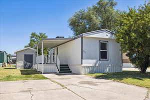 Manufactured / mobile home with a front yard, a storage unit, and a porch
