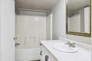 Bathroom with a textured ceiling, vanity, and  shower combination