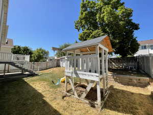 Fenced backyard with a playground, deck and stairs