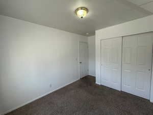 Carpeted 3rd bedroom featuring dark colored carpet and a closet