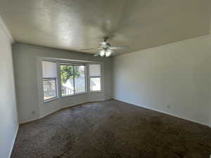Primary bedroom 1 with bay window overlooking backyard, crown molding, carpet, ceiling fan, and a textured ceiling
