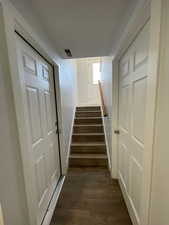 Staircase leading from garage/basement to main entrance, featuring rail and wood finished floors