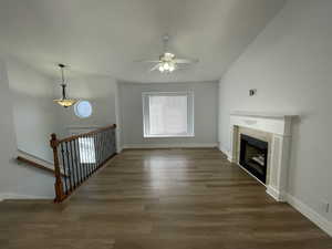 Unfurnished living room with a ceiling fan, wood finished floors, a fireplace, and vaulted ceiling