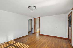 Spare room featuring arched walkways and hardwood / wood-style floors