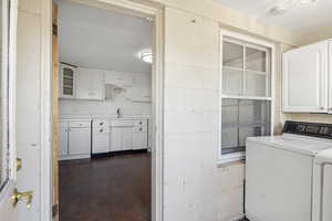 Laundry area with concrete block wall, cabinet space, and independent washer and dryer