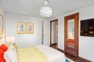 Bedroom with dark wood finished floors and a chandelier