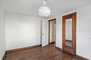 Spare room featuring dark wood-style floors and baseboards