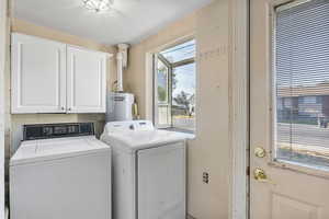 Laundry area with washing machine and clothes dryer, cabinet space, and water heater