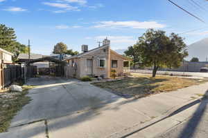 View of front of home with a detached carport, concrete driveway, a chimney, and stucco siding