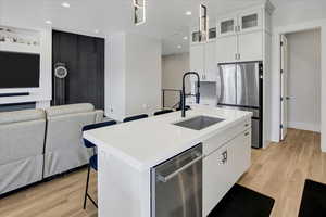 Kitchen with stainless steel appliances, light wood-type flooring, a kitchen island with sink, open floor plan, and recessed lighting