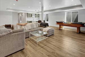 Living area with a raised ceiling, light wood-style floors, recessed lighting, and billiards