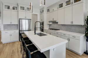 Kitchen featuring appliances with stainless steel finishes, light wood-type flooring, backsplash, a breakfast bar area, and recessed lighting