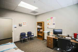 Carpeted office space featuring a paneled ceiling and baseboards