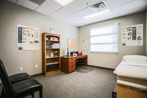 Carpeted home office with a paneled ceiling and baseboards