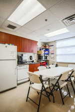 Kitchen with a paneled ceiling, white appliances, and dark countertops