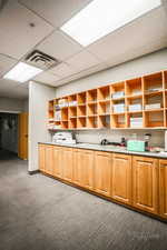 Kitchen with a drop ceiling, open shelves, dark carpet, and light countertops