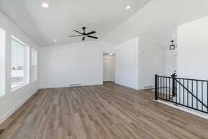 Spare room featuring vaulted ceiling, wood finished floors, ceiling fan, and recessed lighting
