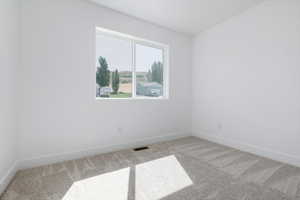 Carpeted spare room featuring baseboards