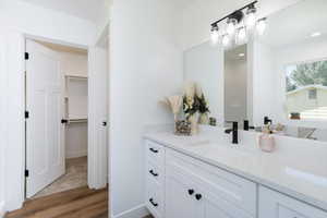 Full bath featuring vanity, wood finished floors, and a walk in closet