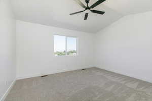 Carpeted spare room with lofted ceiling and ceiling fan