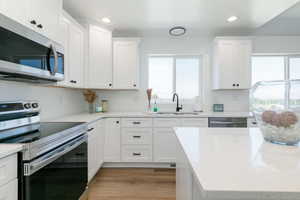 Kitchen featuring stainless steel appliances, white cabinetry, recessed lighting, and light wood-style floors
