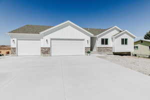 Ranch-style house featuring stone siding, an attached garage, driveway, and roof with shingles
