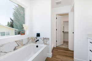Bathroom with a garden tub, vanity, and wood finished floors