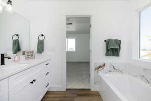 Bathroom with vanity, a garden tub, and wood finished floors