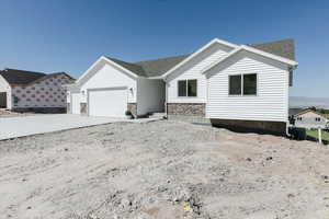 View of front of house featuring stone siding, a garage, and roof with shingles