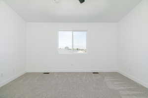 Carpeted spare room featuring baseboards and ceiling fan