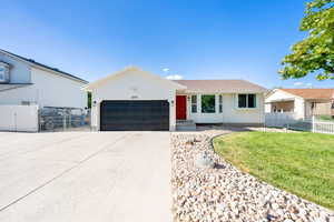 Ranch-style house with concrete driveway, a garage, and a gate