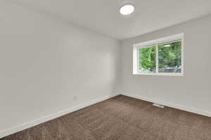 Unfurnished room featuring baseboards and dark colored carpet