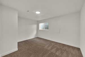 Spare room with dark colored carpet and baseboards