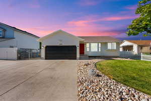 Ranch-style house featuring driveway, an attached garage, and a gate