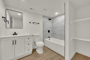 Full bath with wood finished floors, vanity, shower / tub combination, and recessed lighting