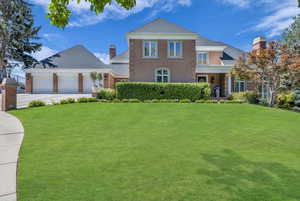View of front of house featuring a front lawn, brick siding, a chimney, and concrete driveway