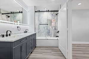 Bathroom with shower / bath combination with glass door, light wood finished floors, and double vanity