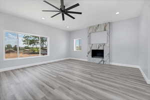 Unfurnished living room with light wood-type flooring, ceiling fan, recessed lighting, and a fireplace