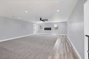 Unfurnished living room featuring recessed lighting, ceiling fan, light wood-style flooring, and a glass covered fireplace