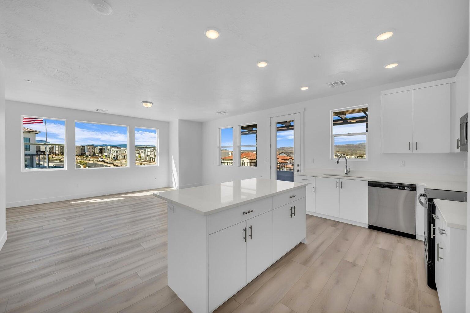 Kitchen with black range, a kitchen island, dishwasher, light wood-type flooring, and light countertops